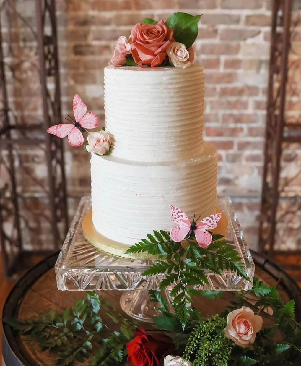 Two-tier wedding cake decorated with roses and butterflies
